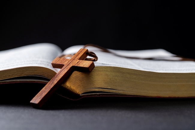 Wooden cross and bible on the table.