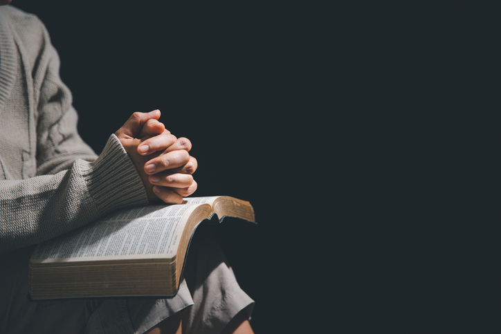 Woman praying with bible in her lap